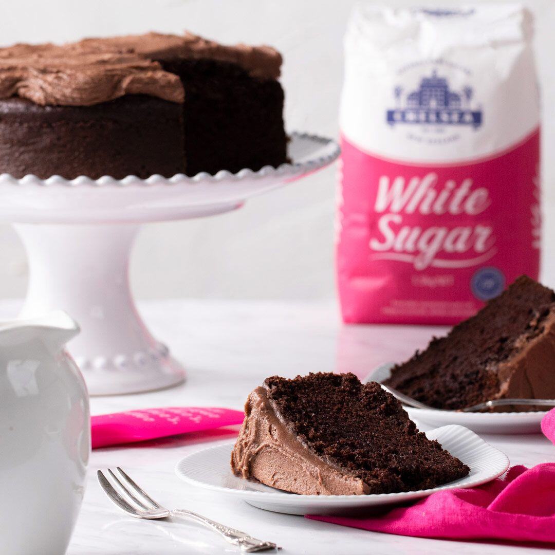 Easy chocolate cake made with Chelsea Sugar on a white plate dusted with cocoa powder